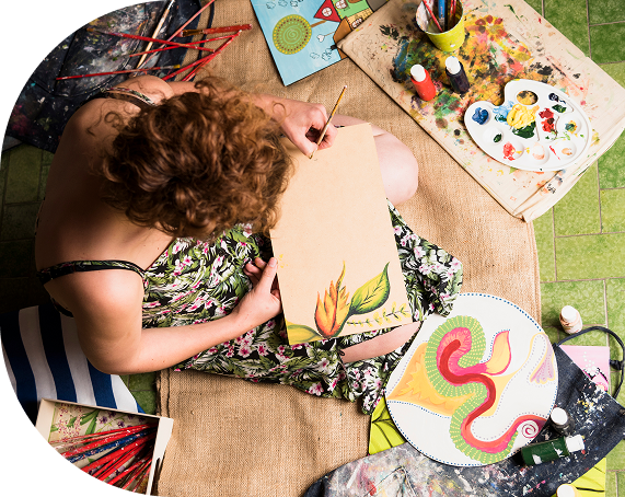 Mujer pintando en el suelo rodeada de materiales de arte