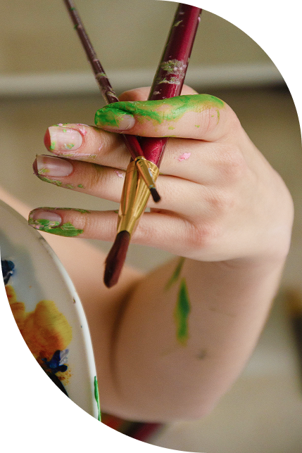 Mano manchada de pintura sosteniendo pinceles